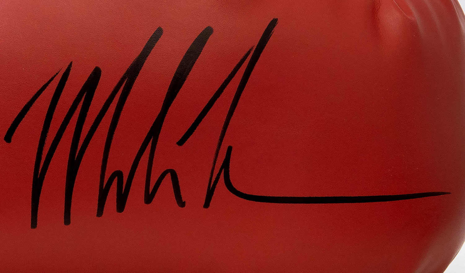 Mike Tyson autograph on red boxing glove in black ink.